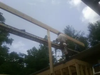 Carpenter setting a ridge beam over a new addition frame — Ice Dam Removal by Roofing Brothers in Mount Freedom