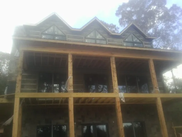 Dormers and porch framing on a large log home under construction — Roof Coating work by our crew in Mount Freedom