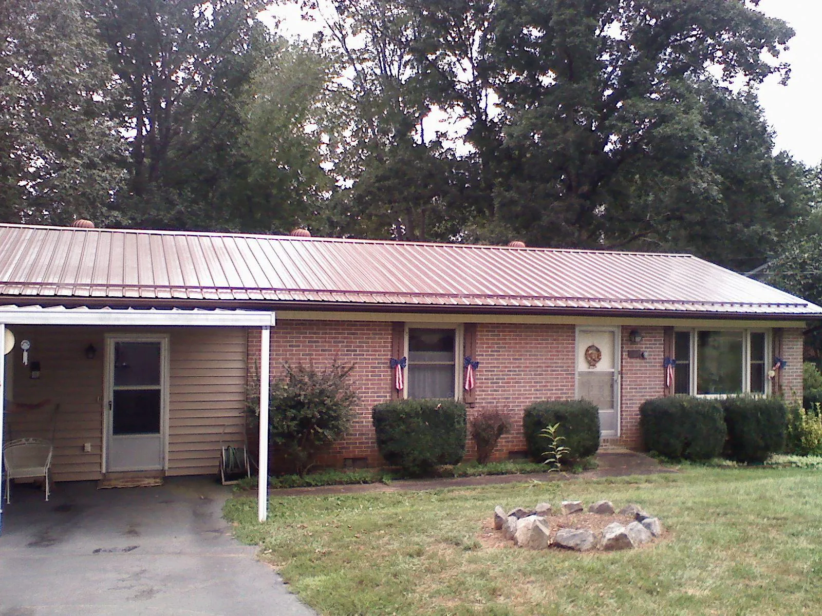 Bronze metal roof and carport on a brick ranch home — Roof Repair work by our crew in Mount Freedom